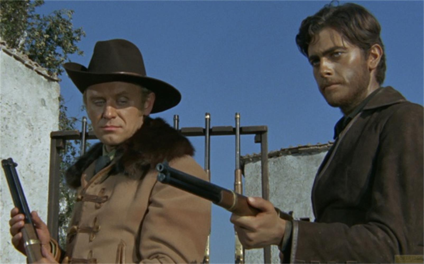 Due uomini con cappelli da cowboy tengono fucili. Uno indossa un cappotto marrone con colletto di pelliccia.