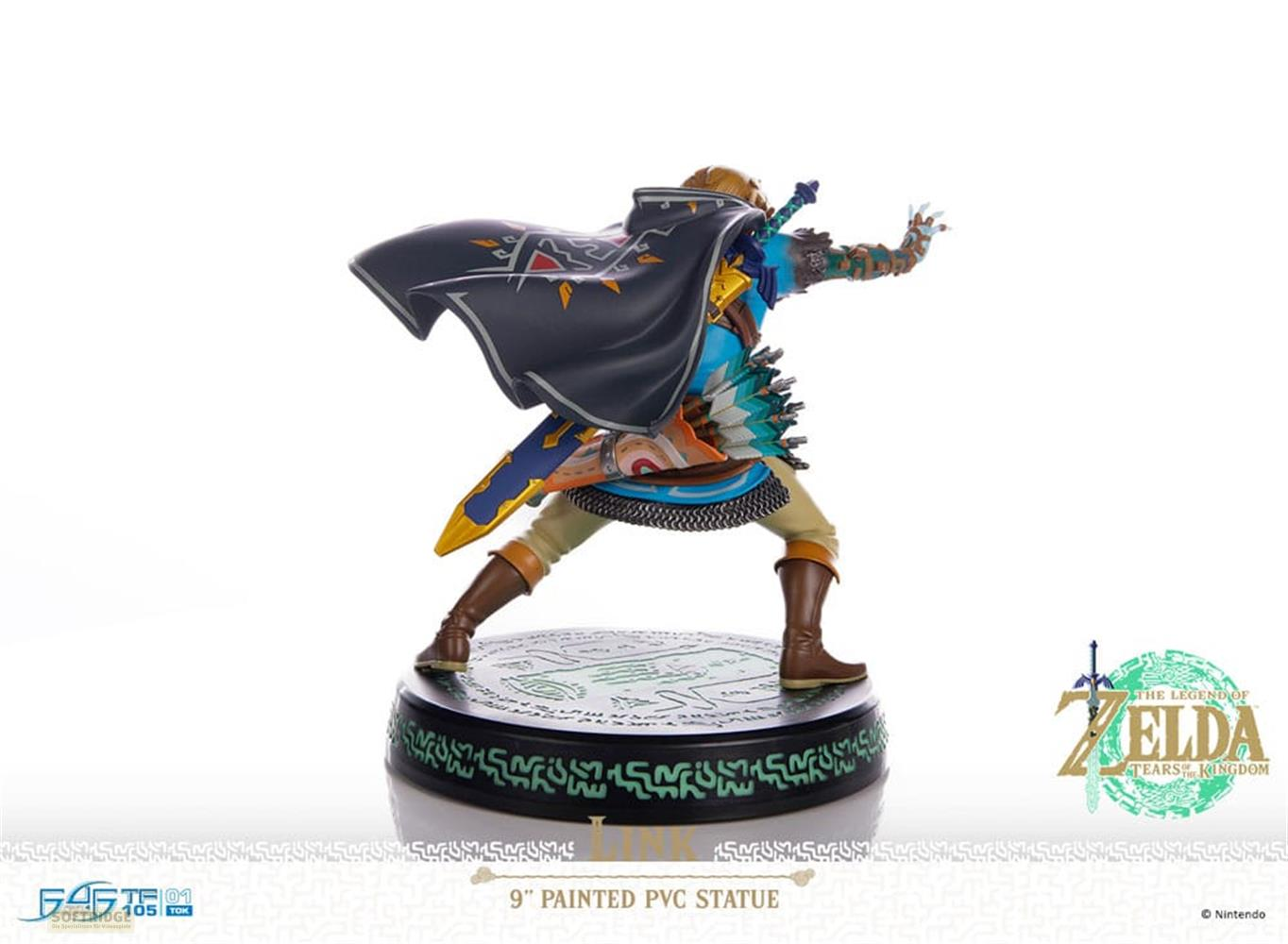 Una estatua de Link de PVC con capa negra y traje azul sobre un pedestal.