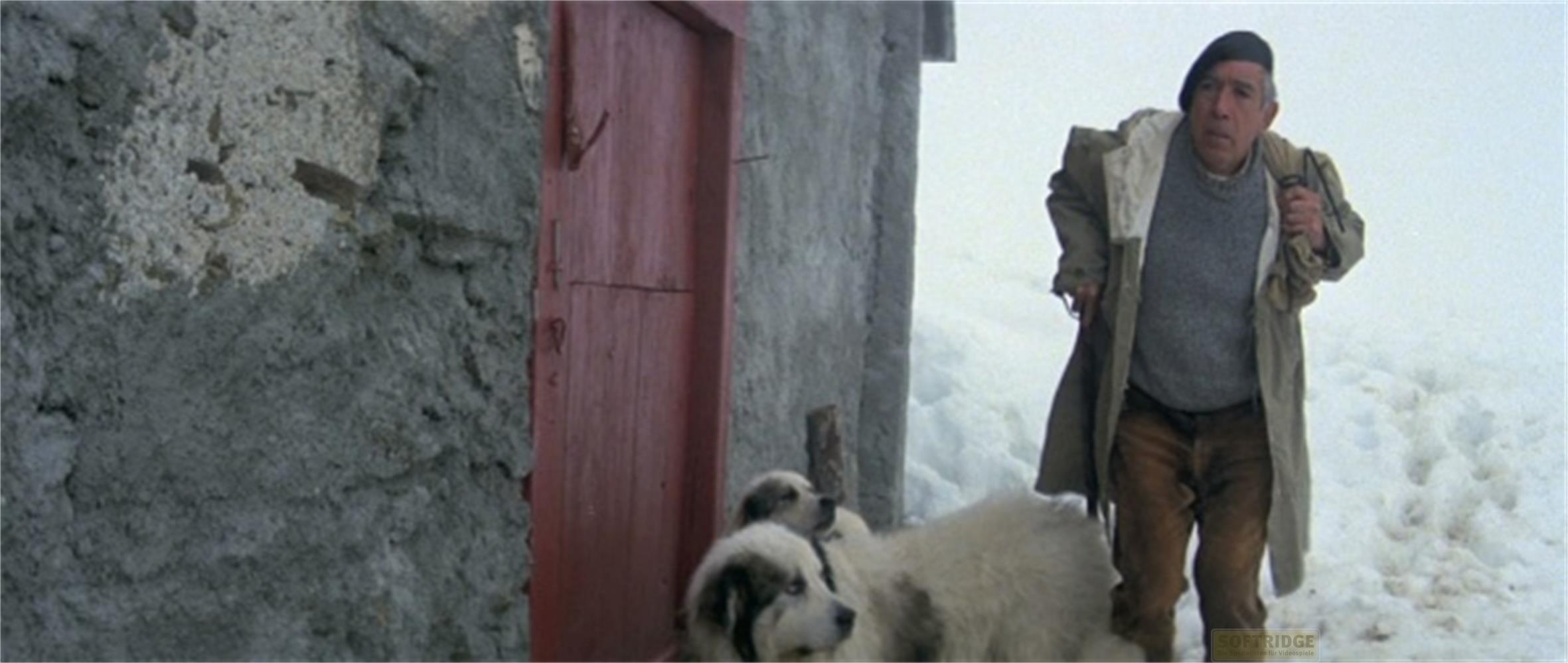 Un uomo con basco e cani vicino a una porta nella neve.