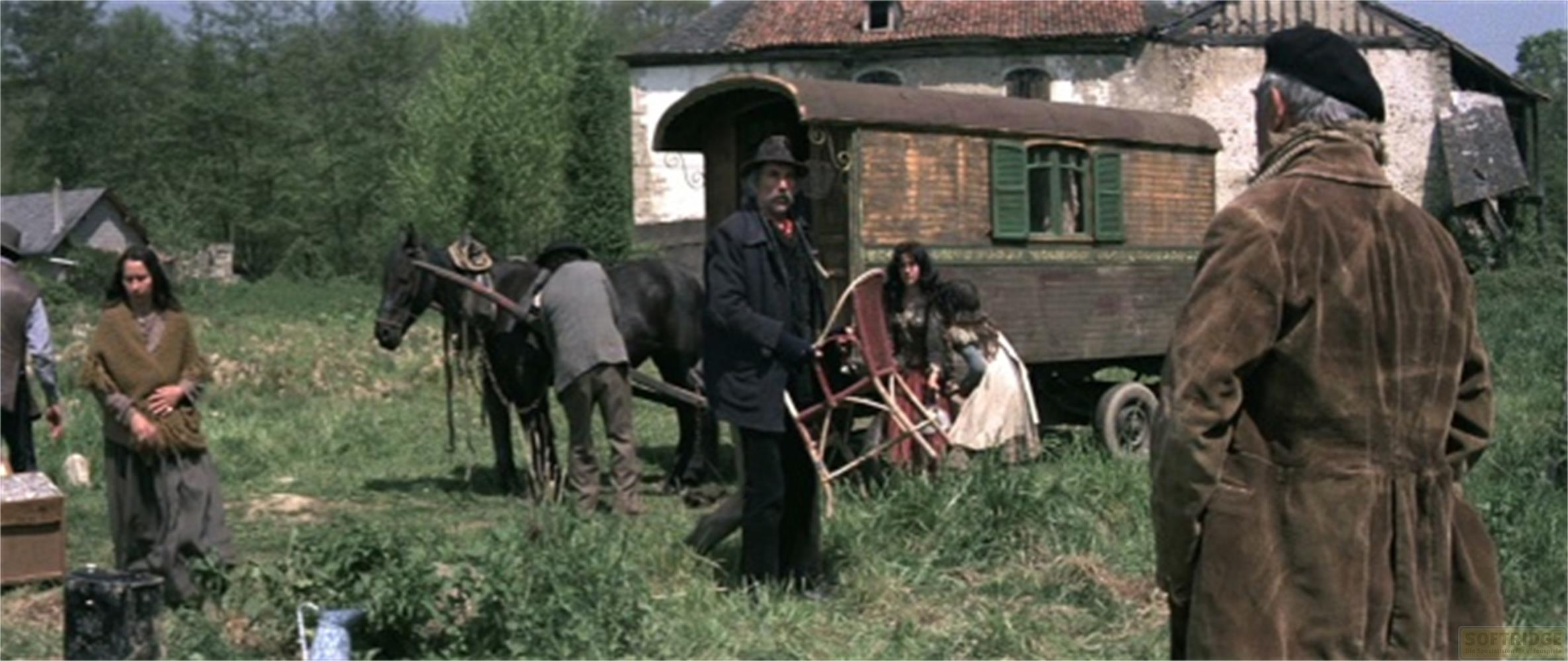Una famiglia di zingari con cavallo e roulotte in un campo davanti a una vecchia casa.
