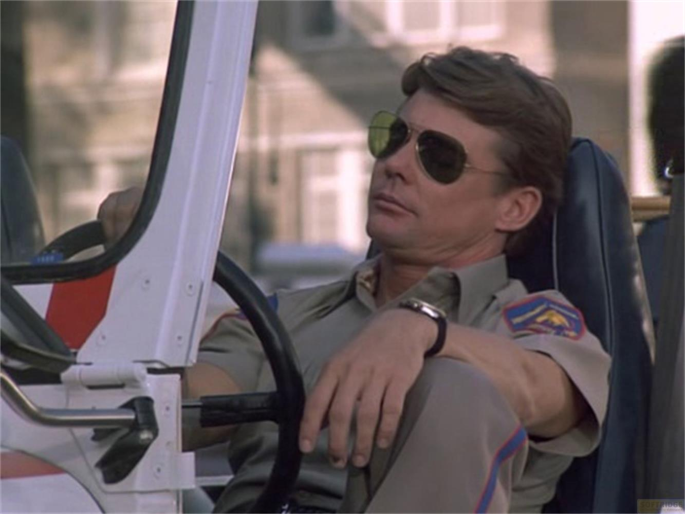 Un uomo in uniforme con occhiali da sole è al volante di un veicolo.