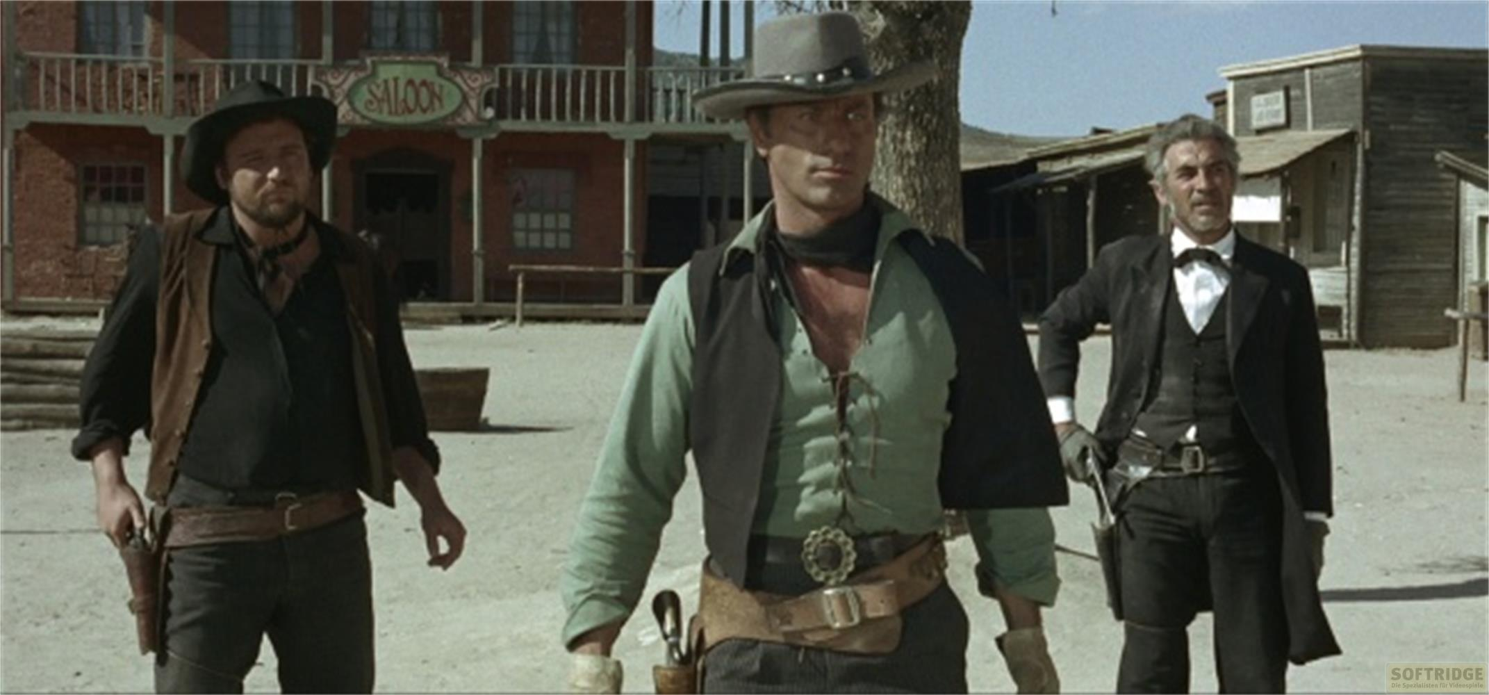 Tre uomini in abiti western davanti a un saloon e edifici in legno.