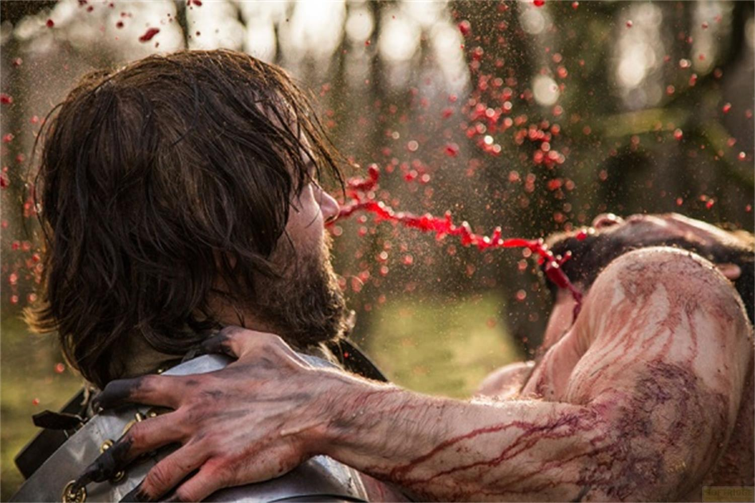 Un uomo sputa sangue mentre un altro viene tenuto da dietro.