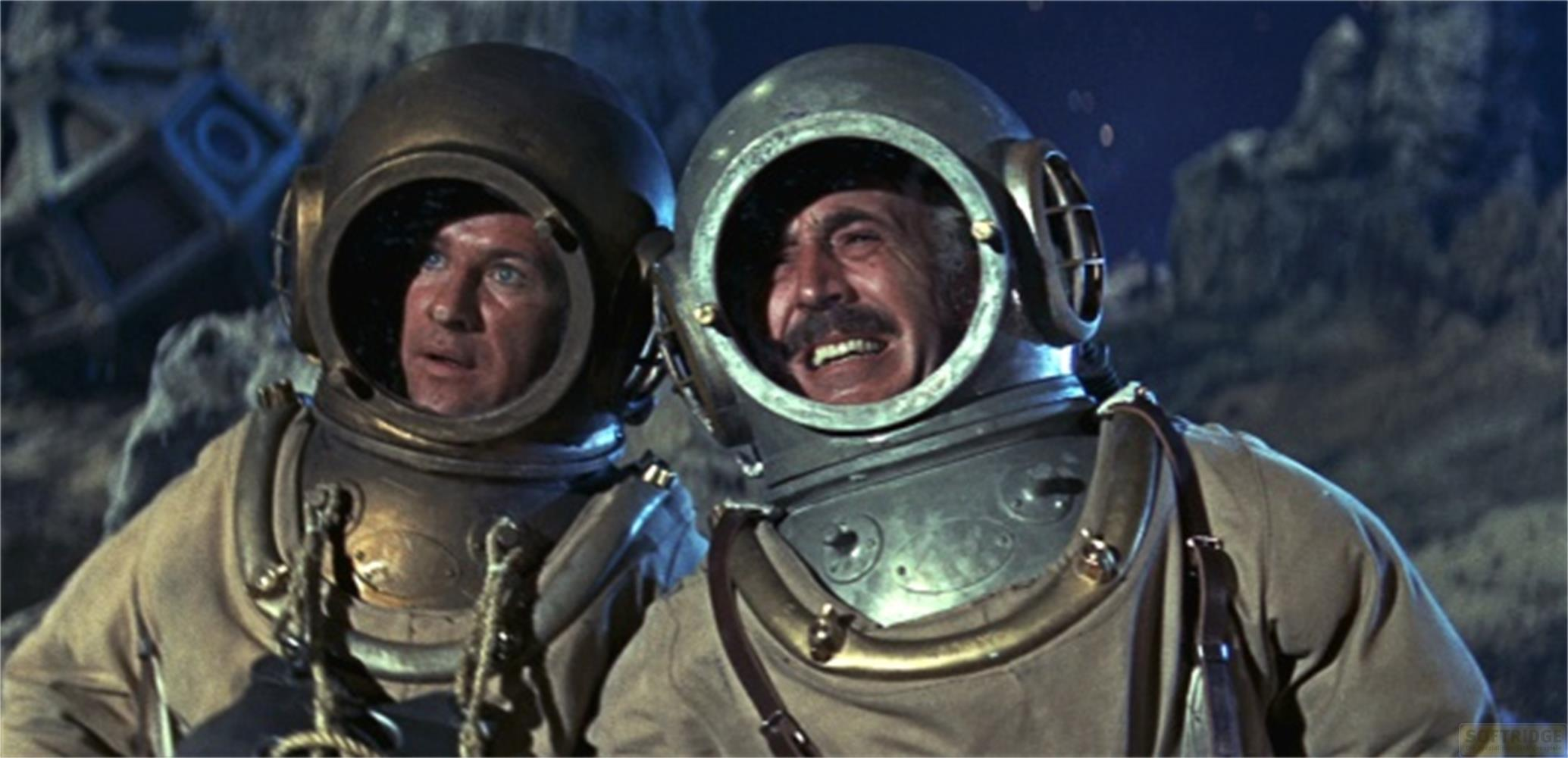 Deux plongeurs en casques vintage, l'un rit, l'autre a l'air inquiet.