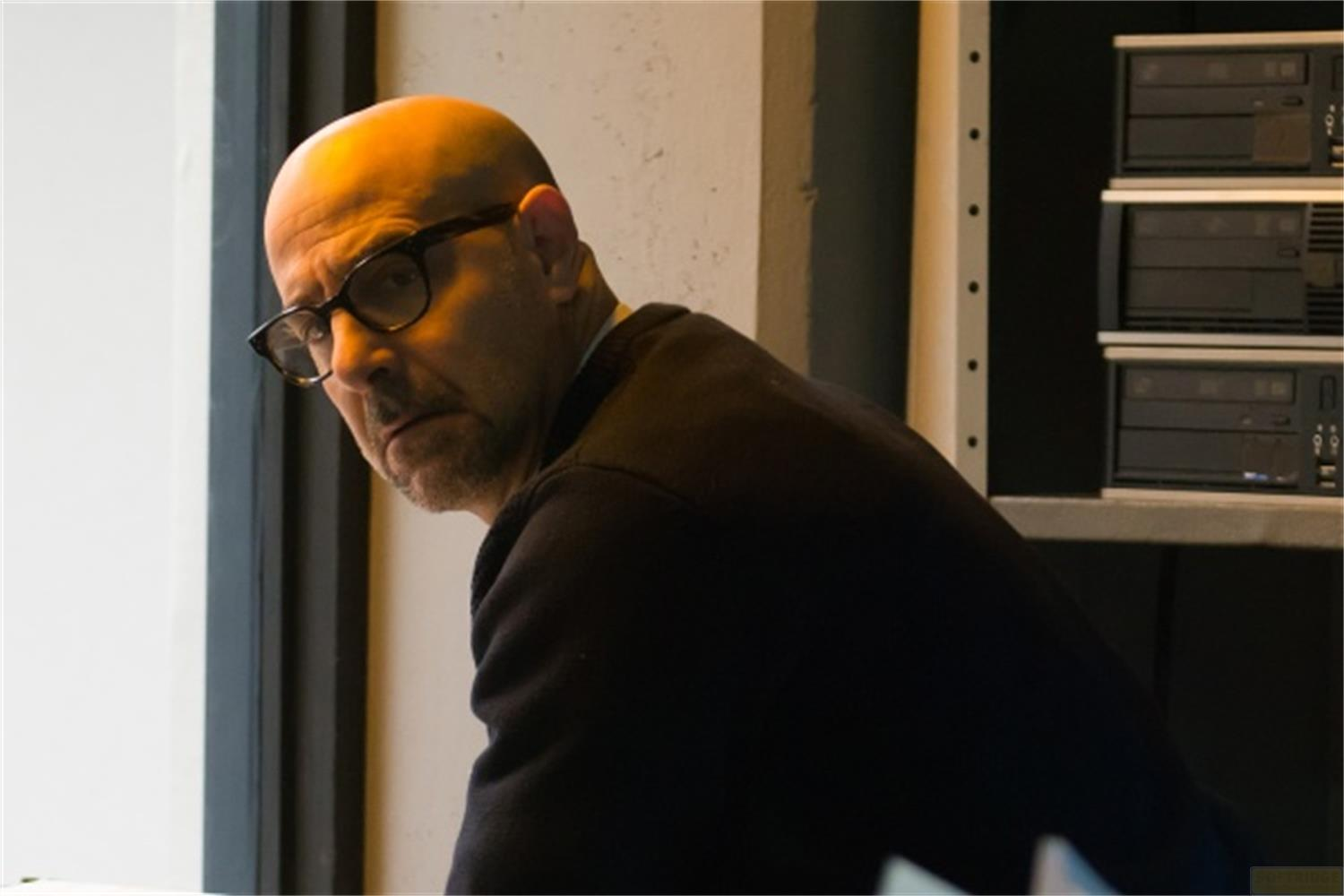 Ein Mann mit Glatze und Brille blickt nach links. Er trägt ein dunkles Oberteil.