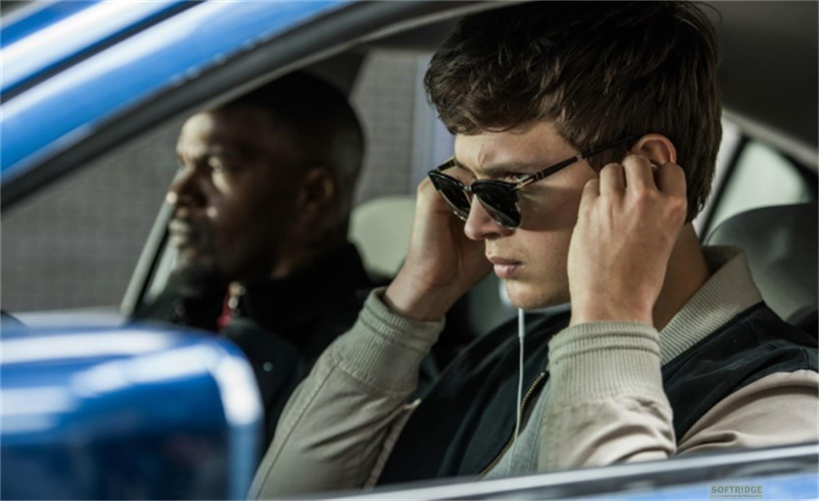 Homme avec lunettes de soleil et écouteurs dans une voiture, conducteur au fond.