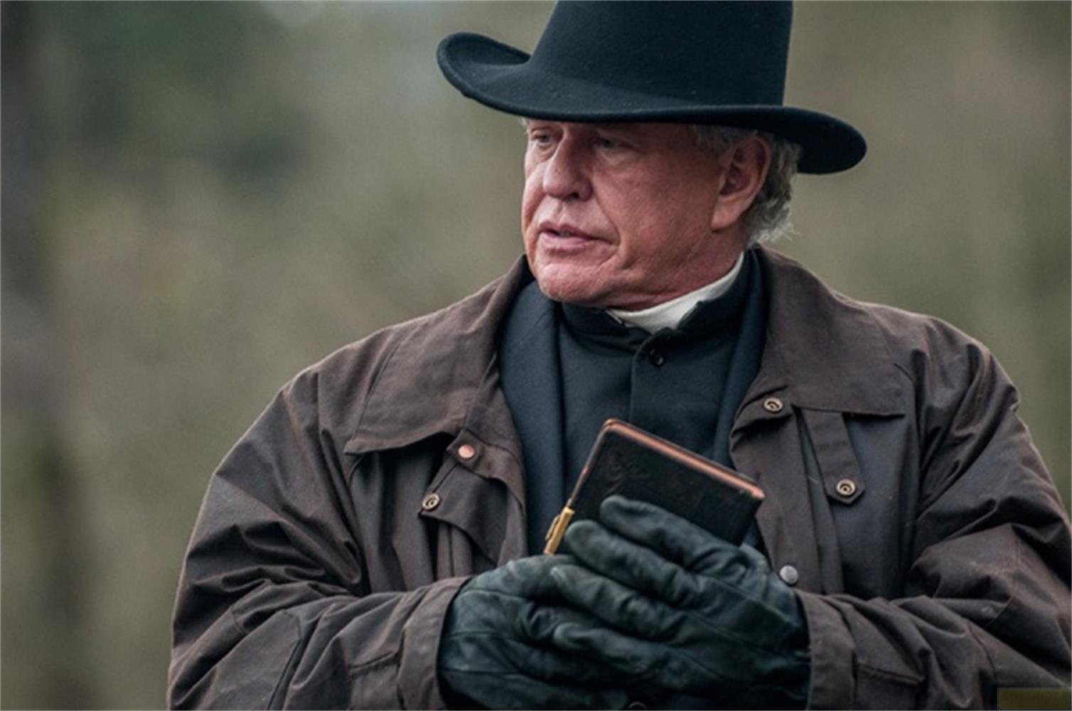 Un homme en chapeau et manteau tient un livre. Chapeau noir, manteau marron.