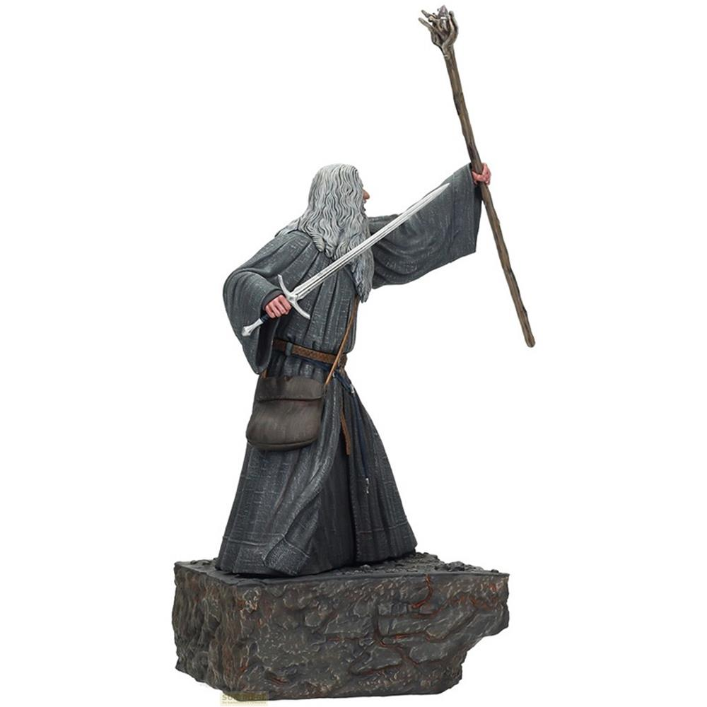Una figura de Gandalf con espada y bastón se alza sobre una base rocosa.