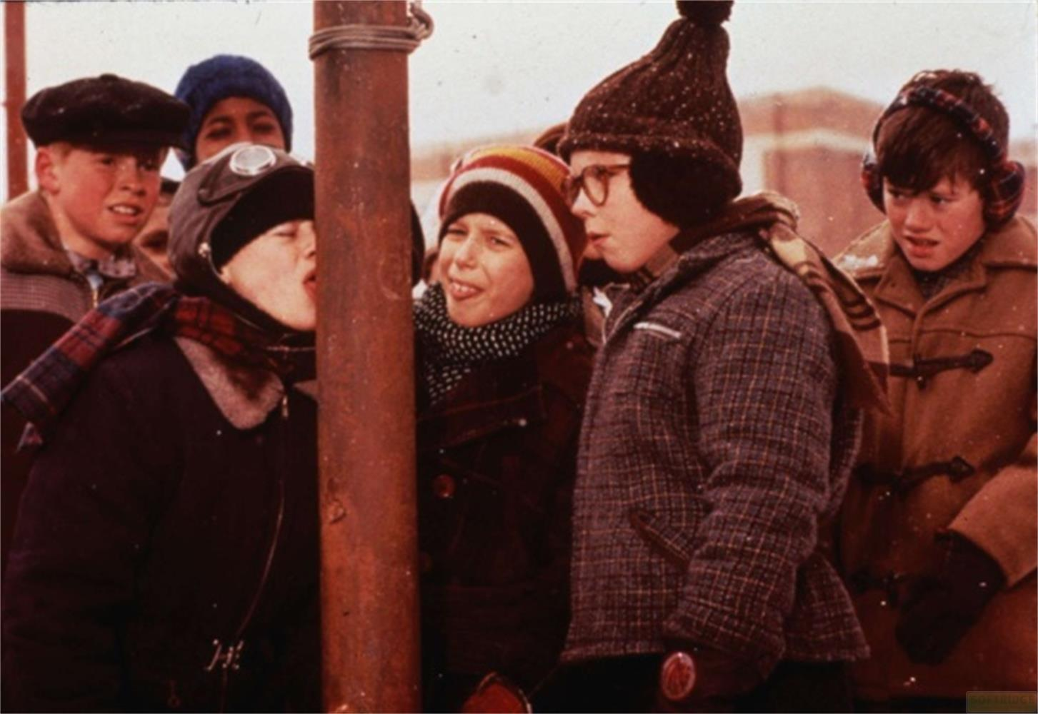 Bambini in abiti invernali fissano un palo arrugginito.
