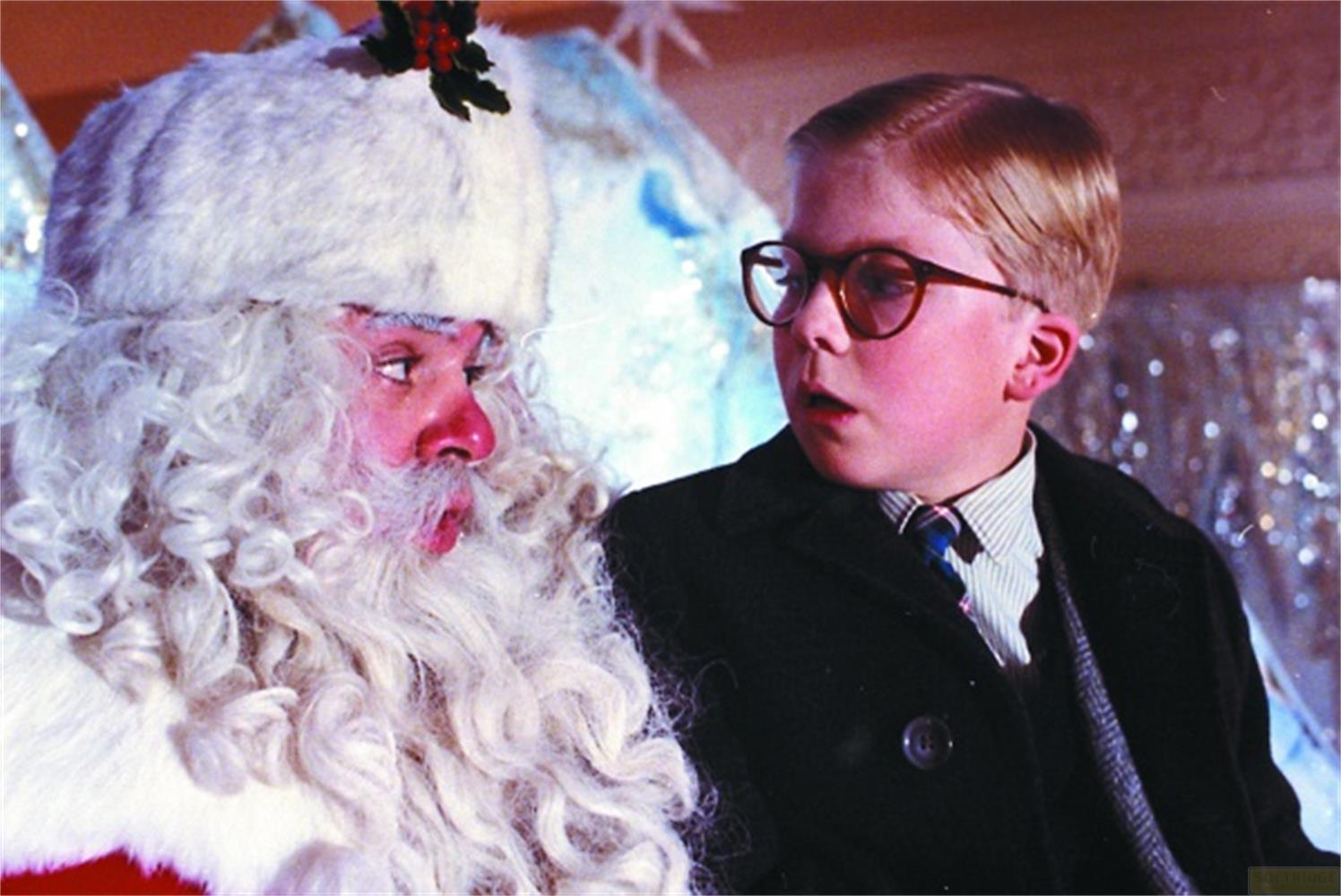 Un ragazzo con gli occhiali parla con Babbo Natale, barba bianca e naso rosso.