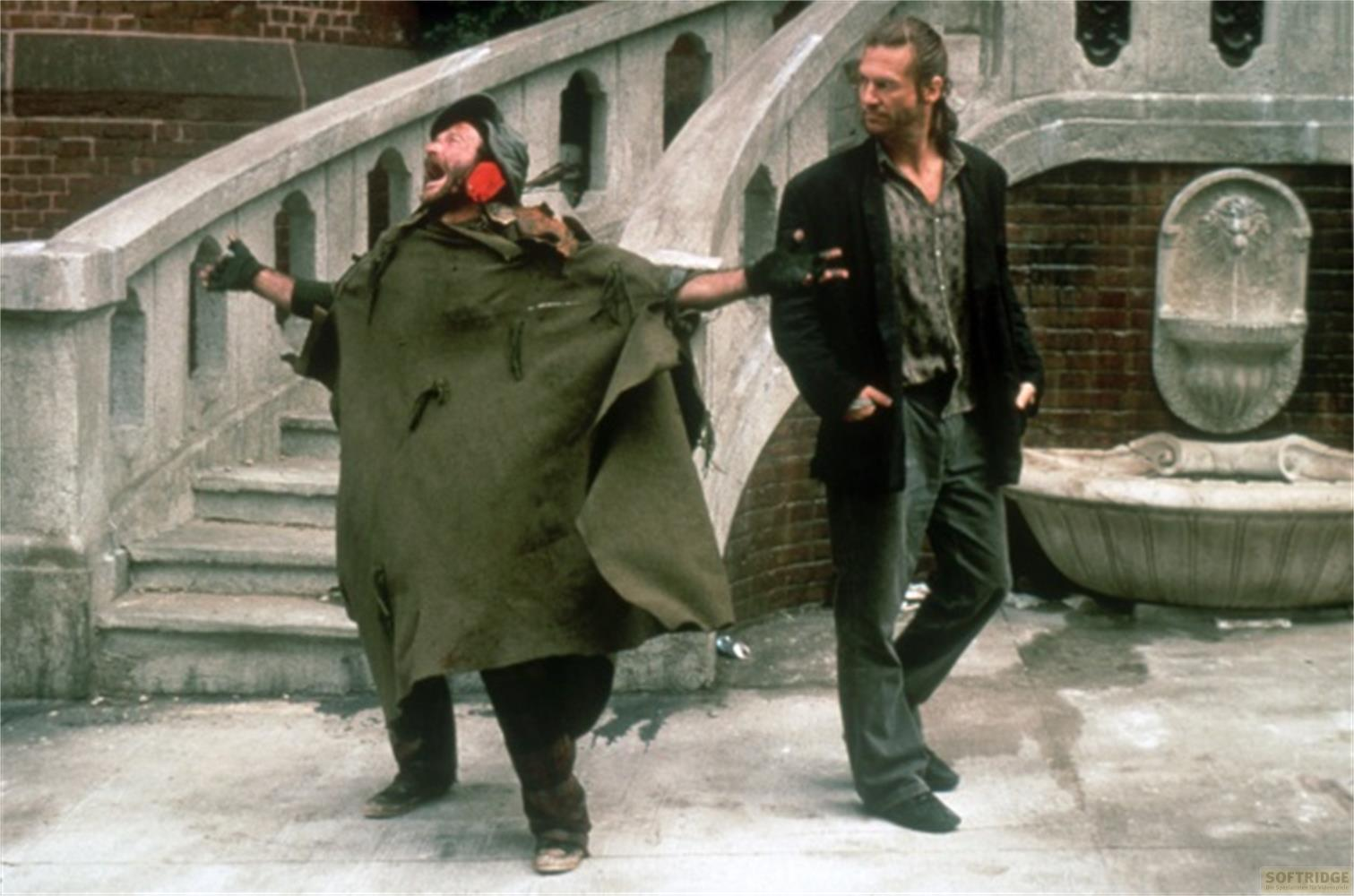 Homme en couverture verte criant à côté d'un homme en veste noire.