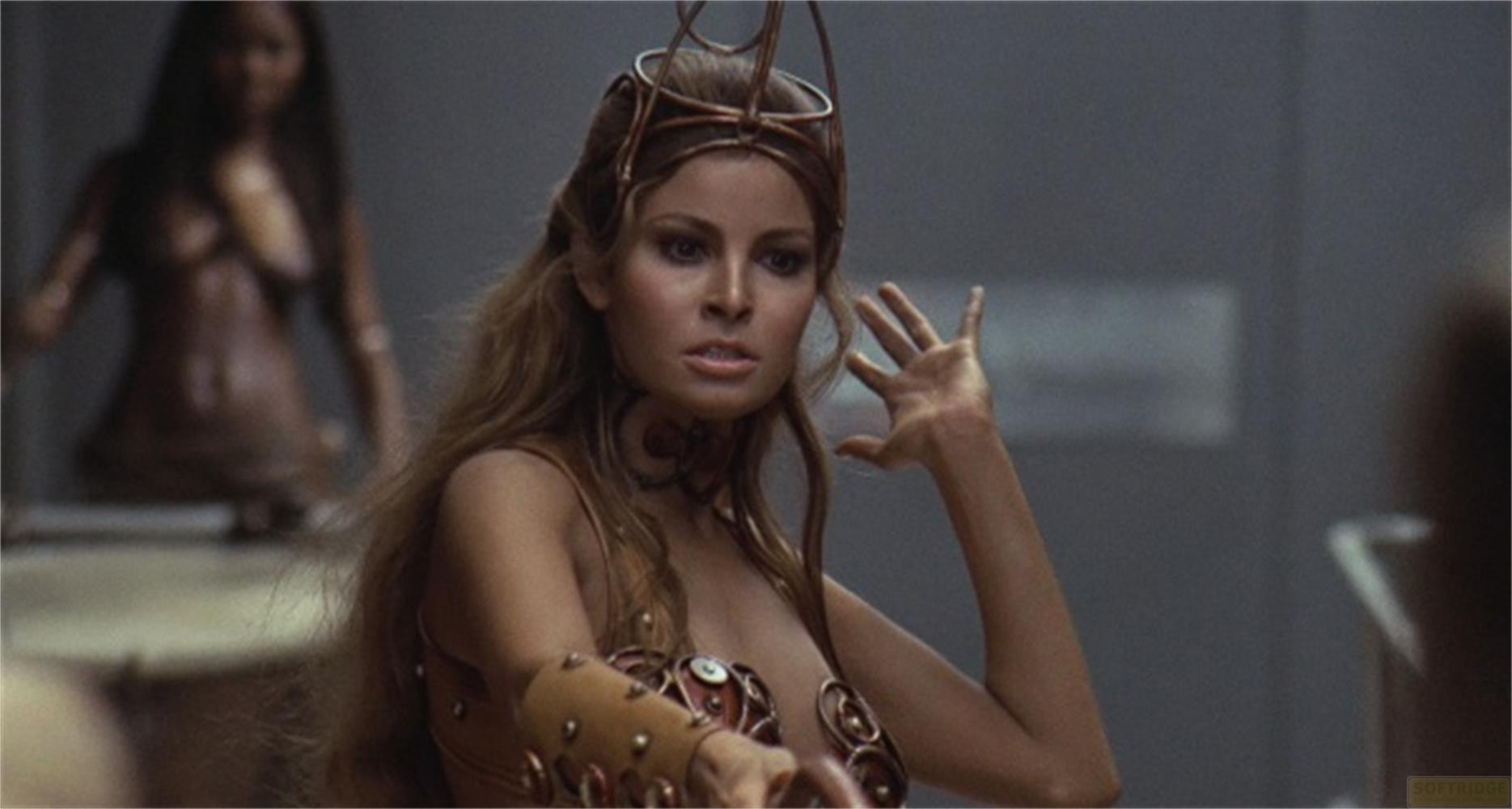 Una donna con lunghi capelli castani indossa un abito di bronzo e una corona.