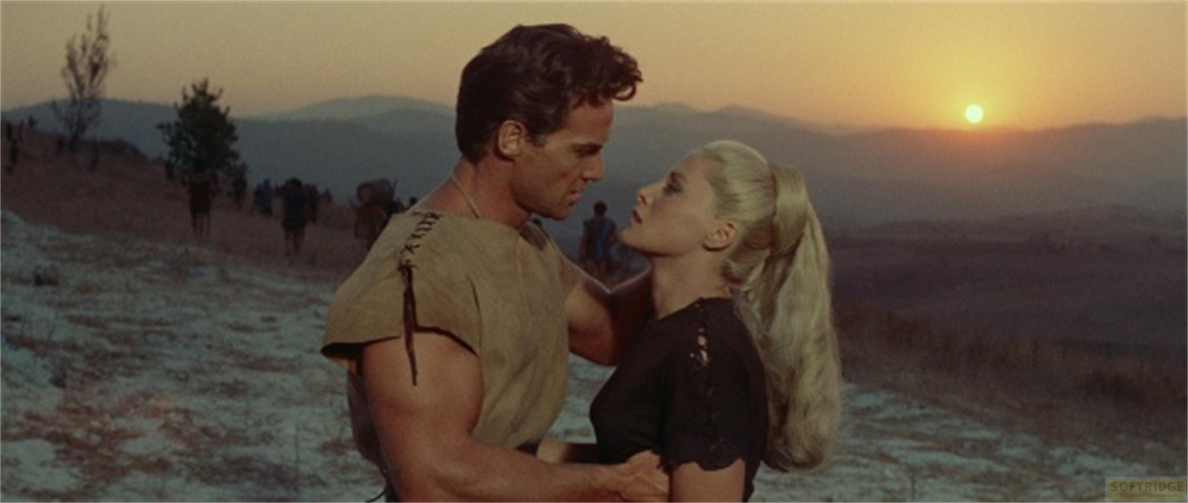 Uomo e donna al tramonto, sfondo con persone che camminano.