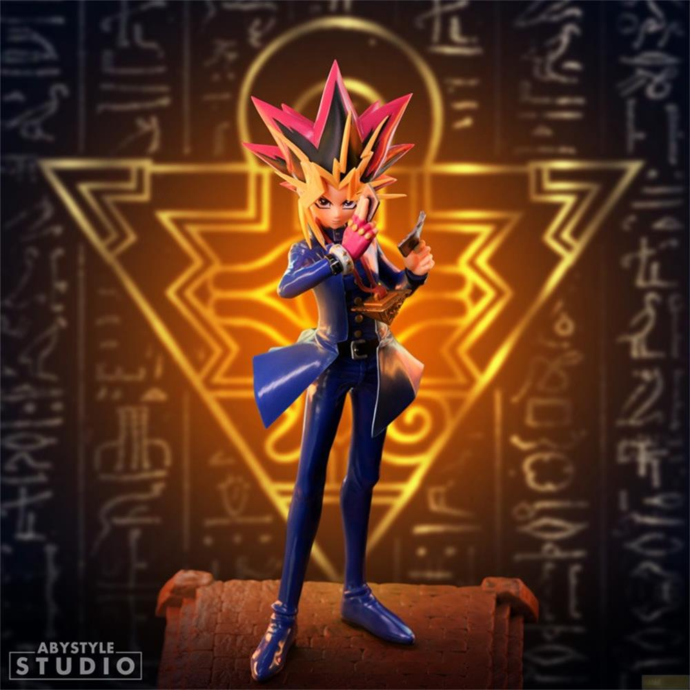 Eine Figur von Yugi Muto steht vor einem goldenen Symbol, die Hände erhoben.