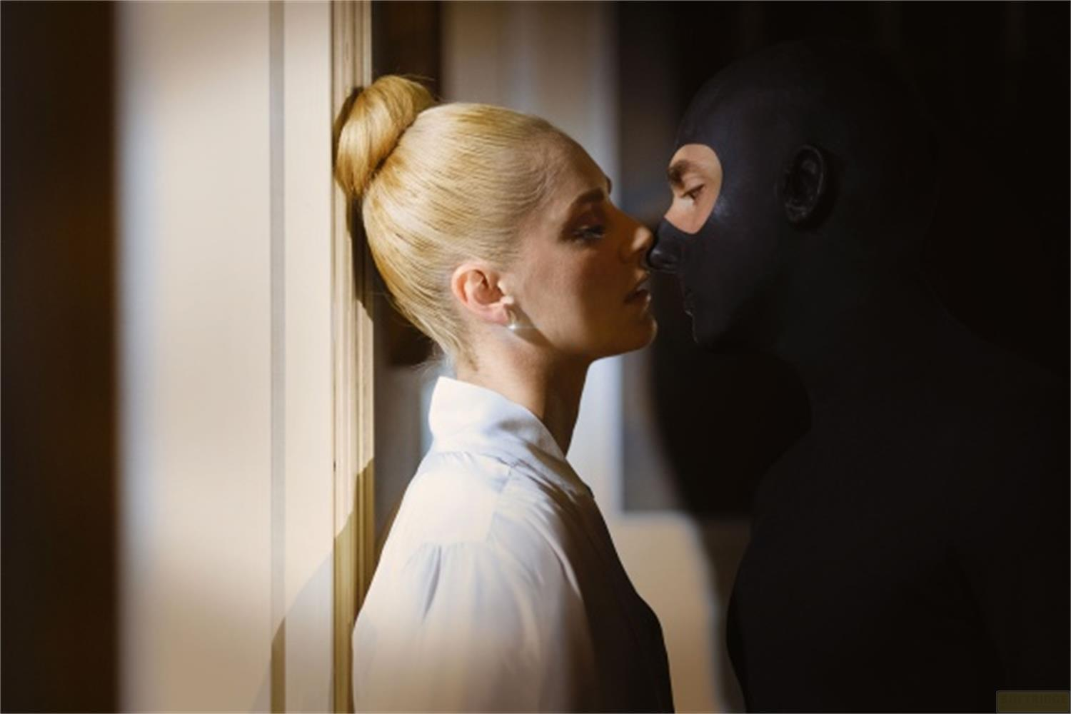 Una donna con chignon biondo e un uomo con maschera nera si fronteggiano.