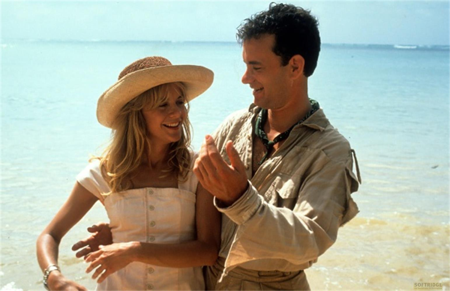 Un uomo e una donna su una spiaggia, si guardano e sorridono. Sfondo oceanico.