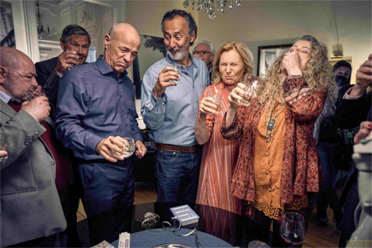 Gruppo di persone con bicchieri, che bevono e fanno smorfie.