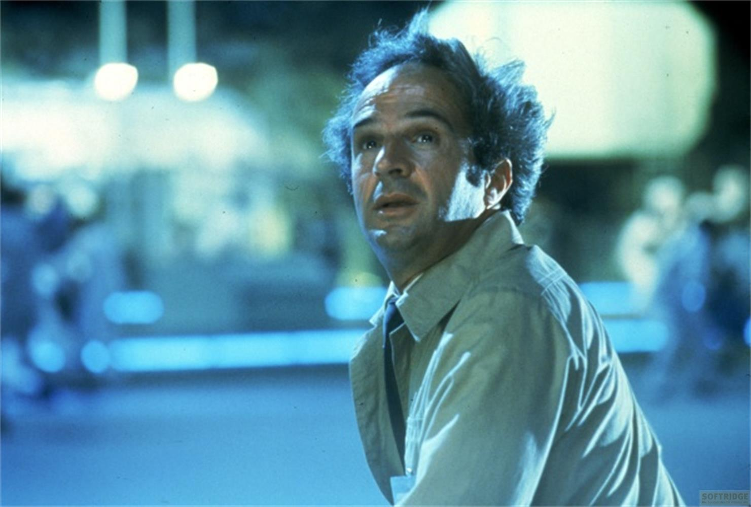 Homme aux cheveux ébouriffés a l'air inquiet, porte une chemise et une veste.