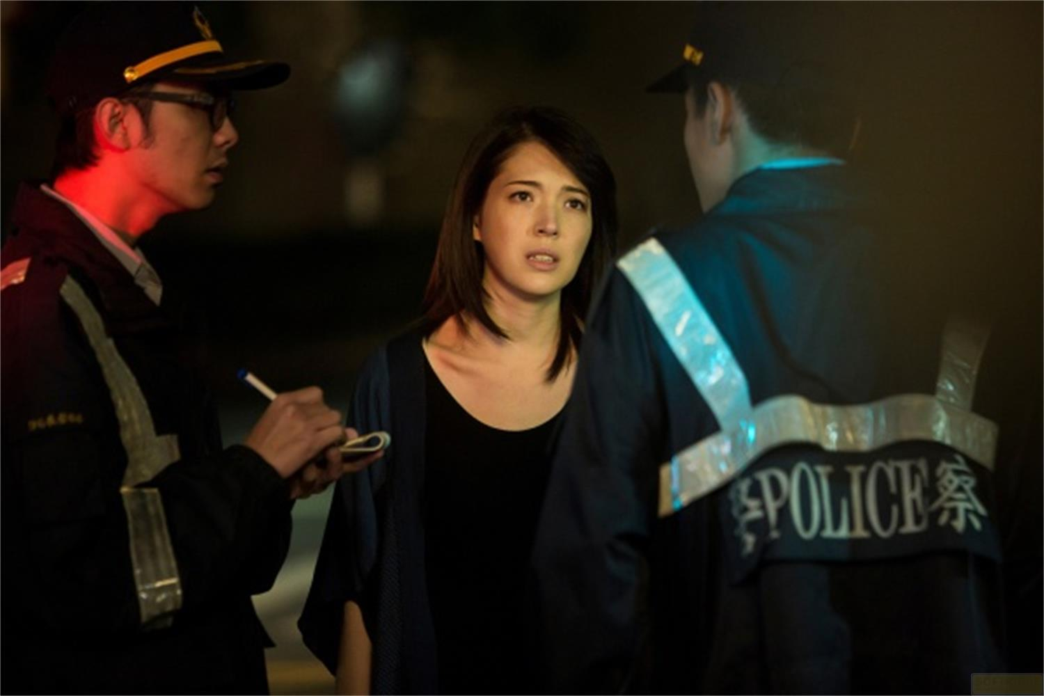 Una donna è tra due poliziotti di notte. Uno scrive qualcosa.