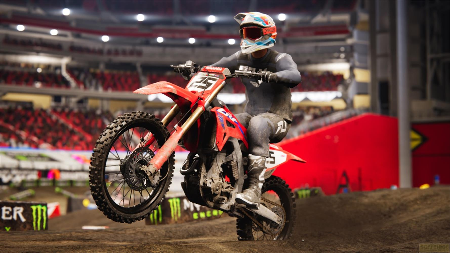 Un pilota di motocross in tenuta completa salta su una moto rossa in un'arena.