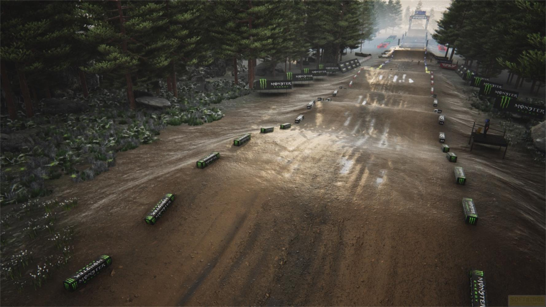 Una pista sterrata fiancheggiata da lattine Monster Energy e alberi, che porta a un salto.