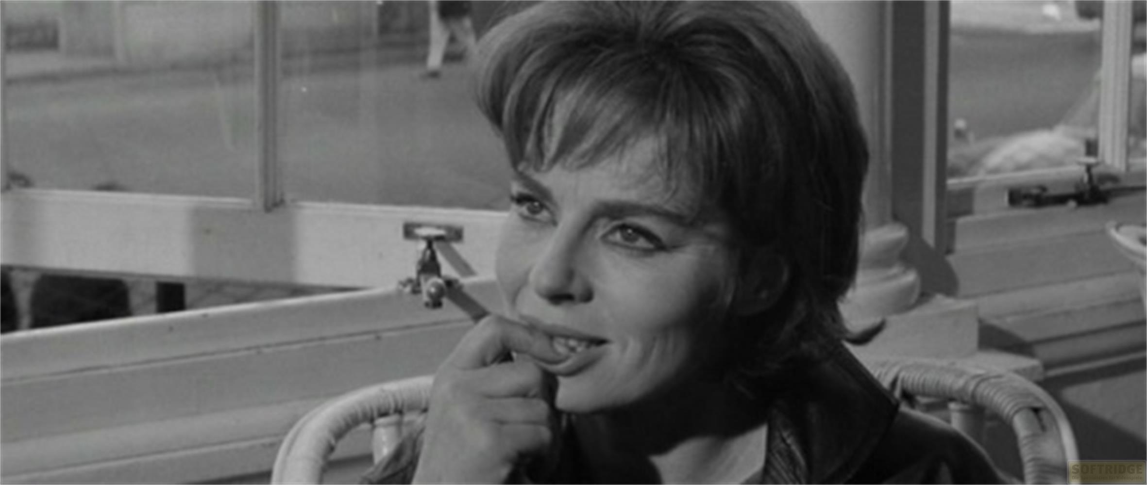 Une femme aux cheveux courts met son doigt dans sa bouche.