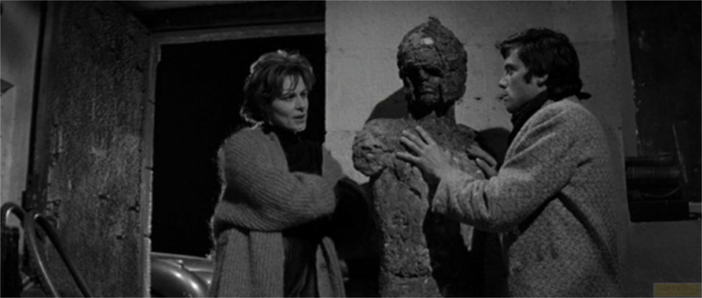 Un homme touche une statue, une femme se tient à côté.