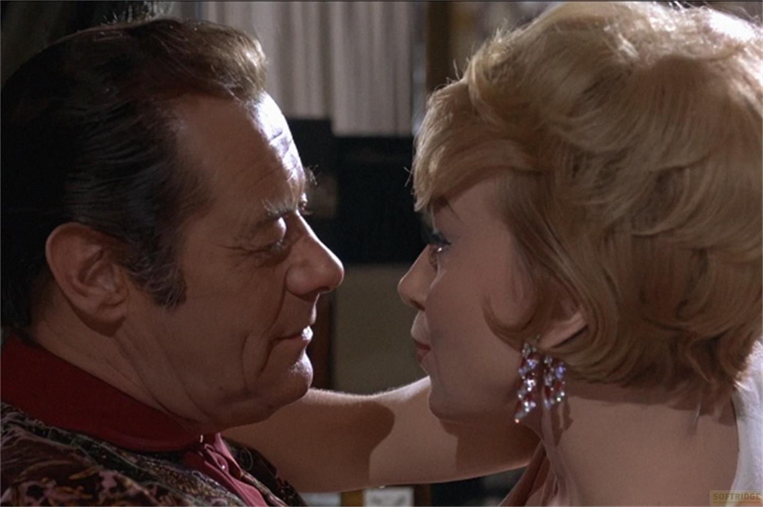 Un uomo e una donna bionda si guardano. Lei indossa orecchini.
