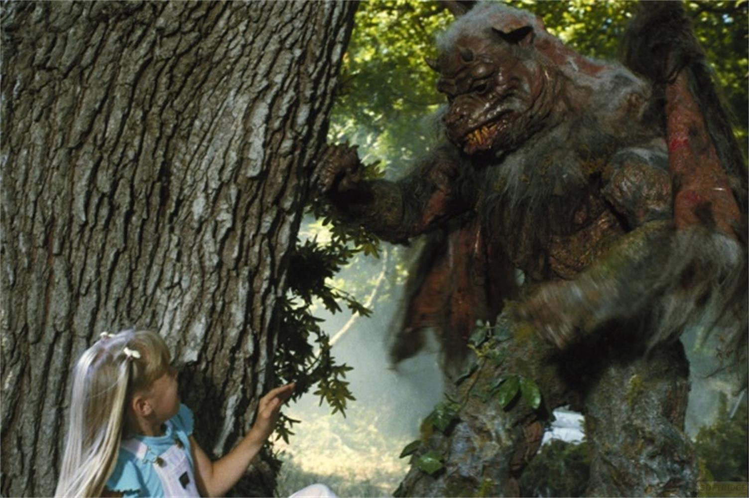Una bambina sta vicino a un albero, guardando un grosso mostro peloso.