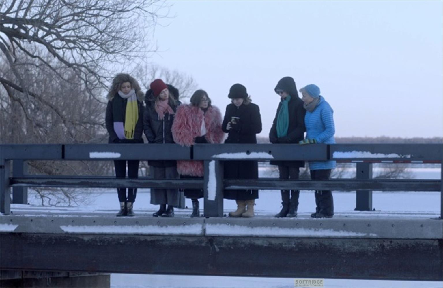 Sei donne in piedi su un ponte innevato.