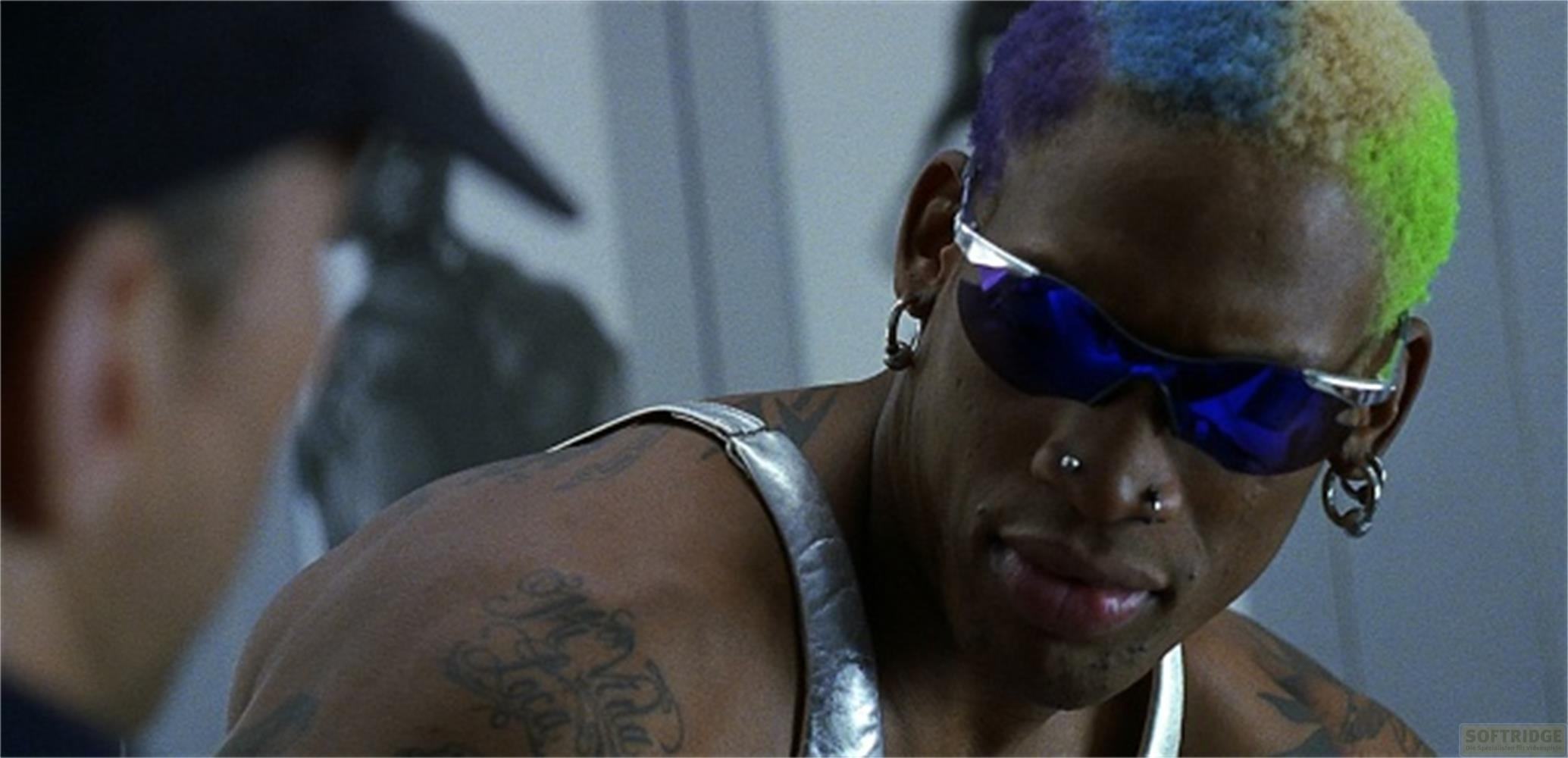 Dennis Rodman avec cheveux colorés, lunettes de soleil et tatouages.
