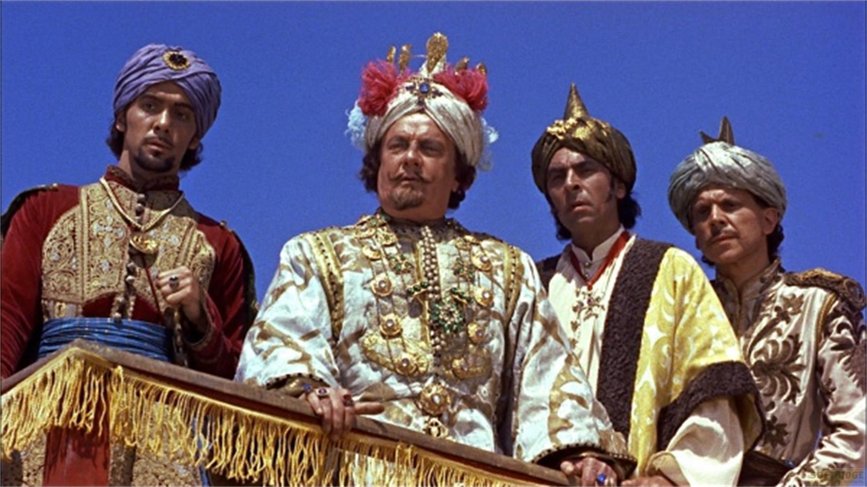 Quatre hommes en costumes et turbans élaborés se tiennent sur une plateforme.