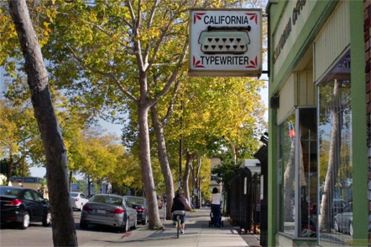 Insegna con macchina da scrivere "California Typewriter" sopra una strada con alberi e auto.