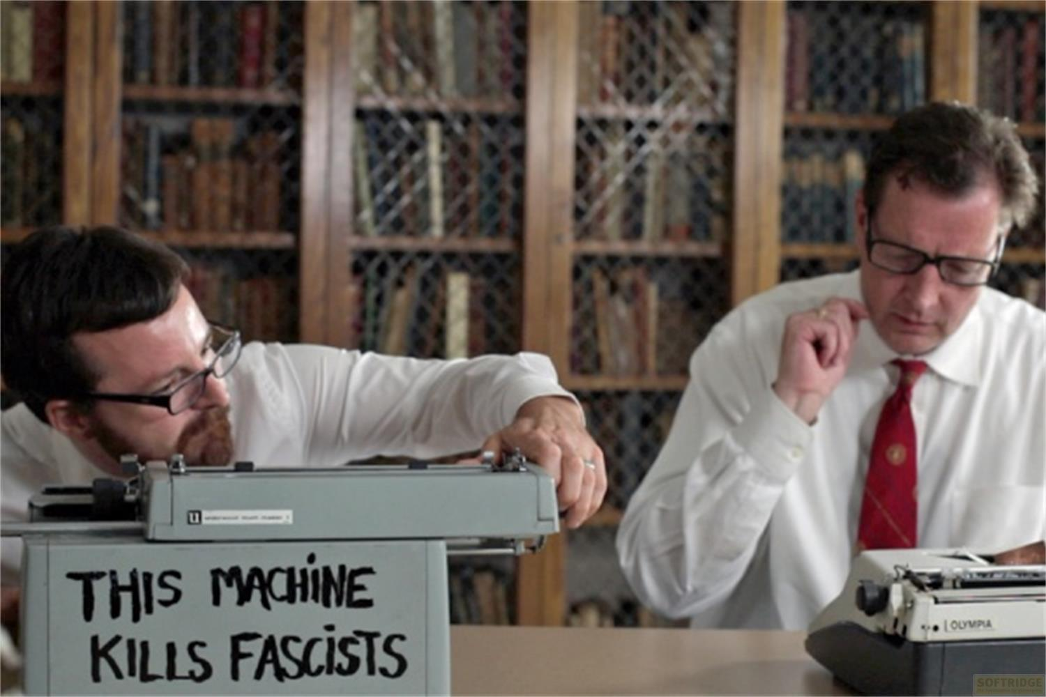 Due uomini seduti a una scrivania davanti a librerie. Uno sta scrivendo a macchina.