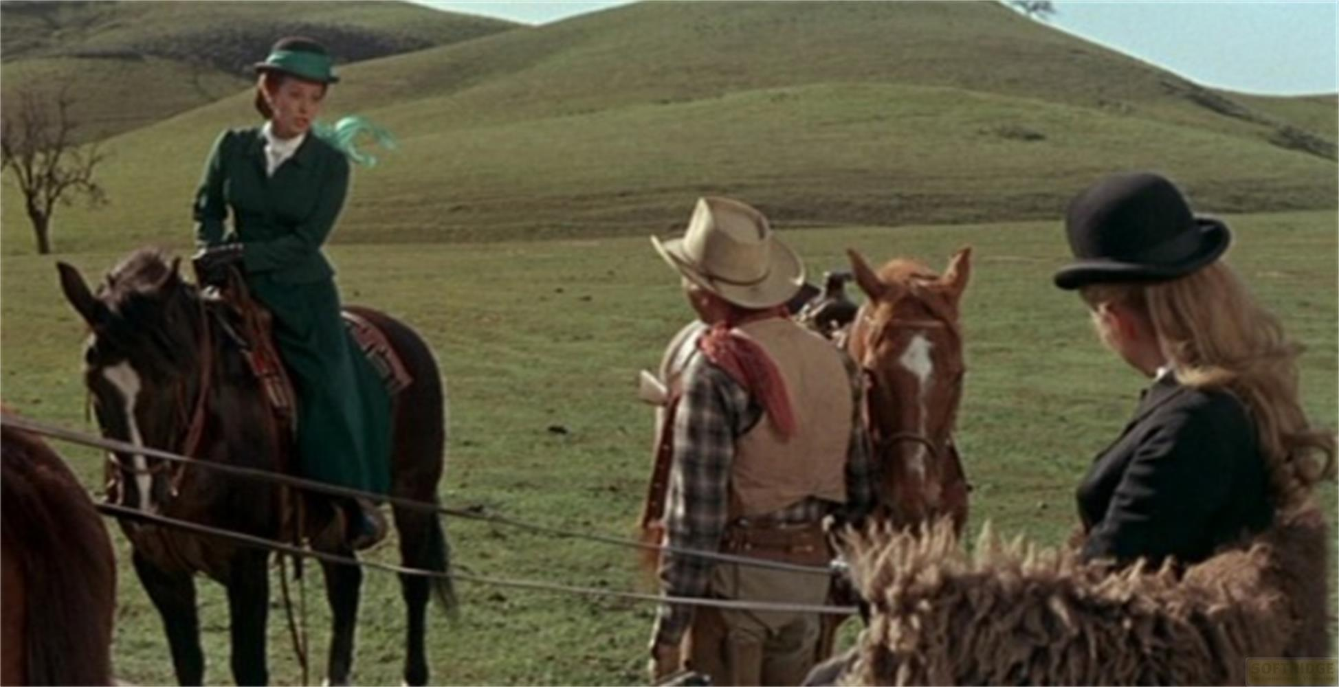 Tre cavalieri a cavallo in un paesaggio verde con colline.