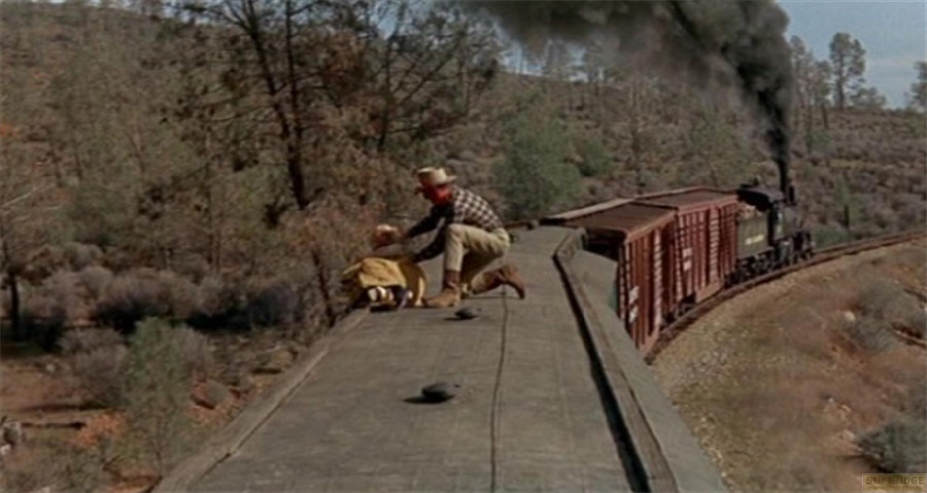 Un uomo in abiti da cowboy su un treno merci con fumo nero.