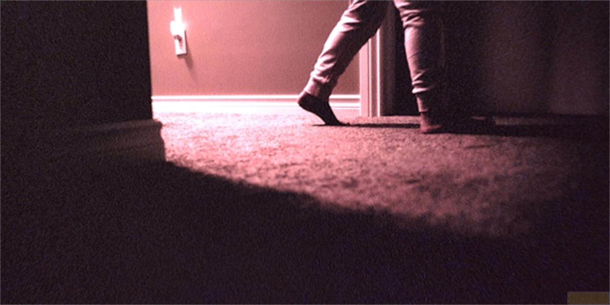 Una persona cammina a piedi nudi sul tappeto. Un interruttore a muro.