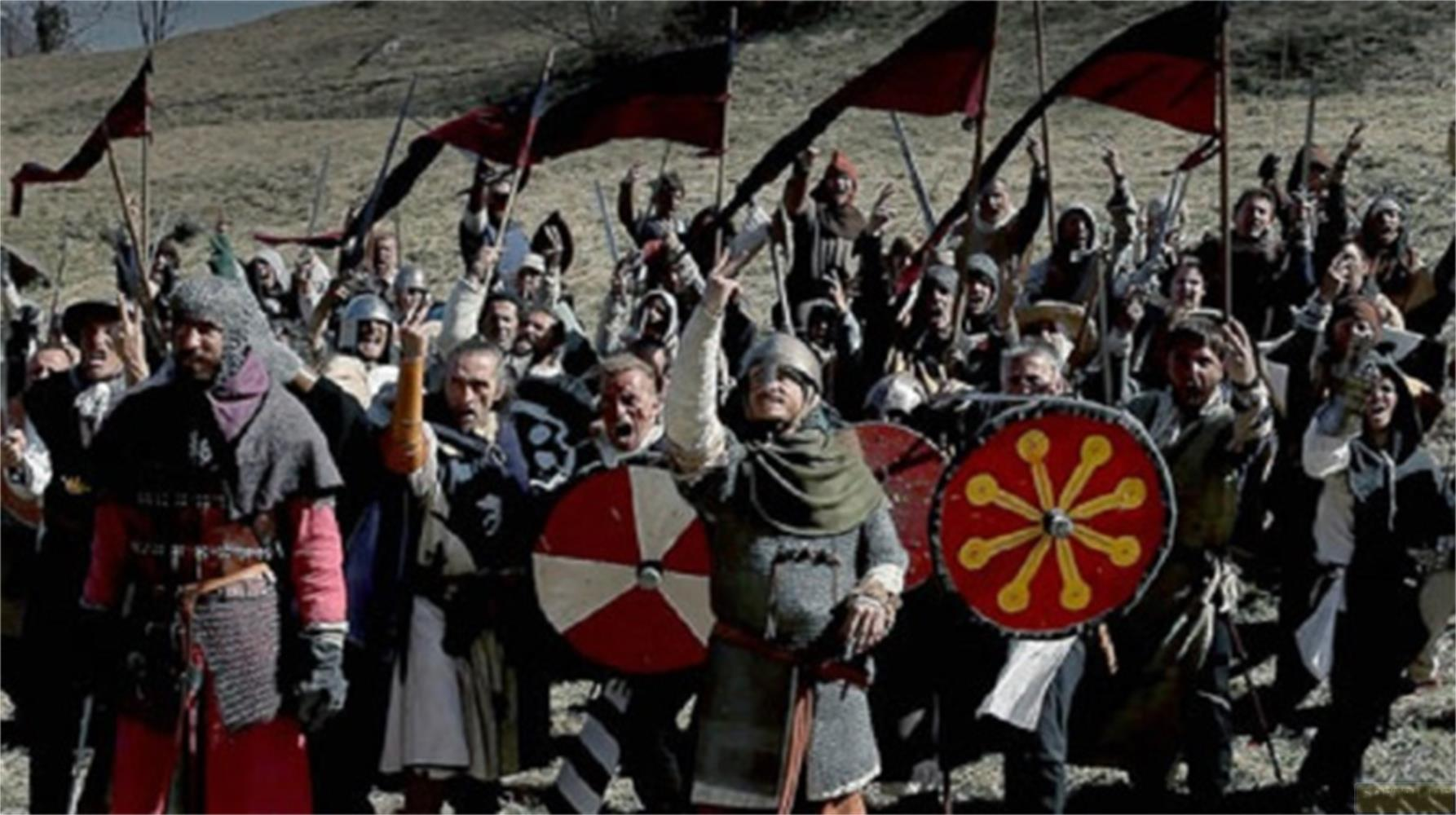 Una folla di guerrieri con armi e bandiere acclama su una collina.