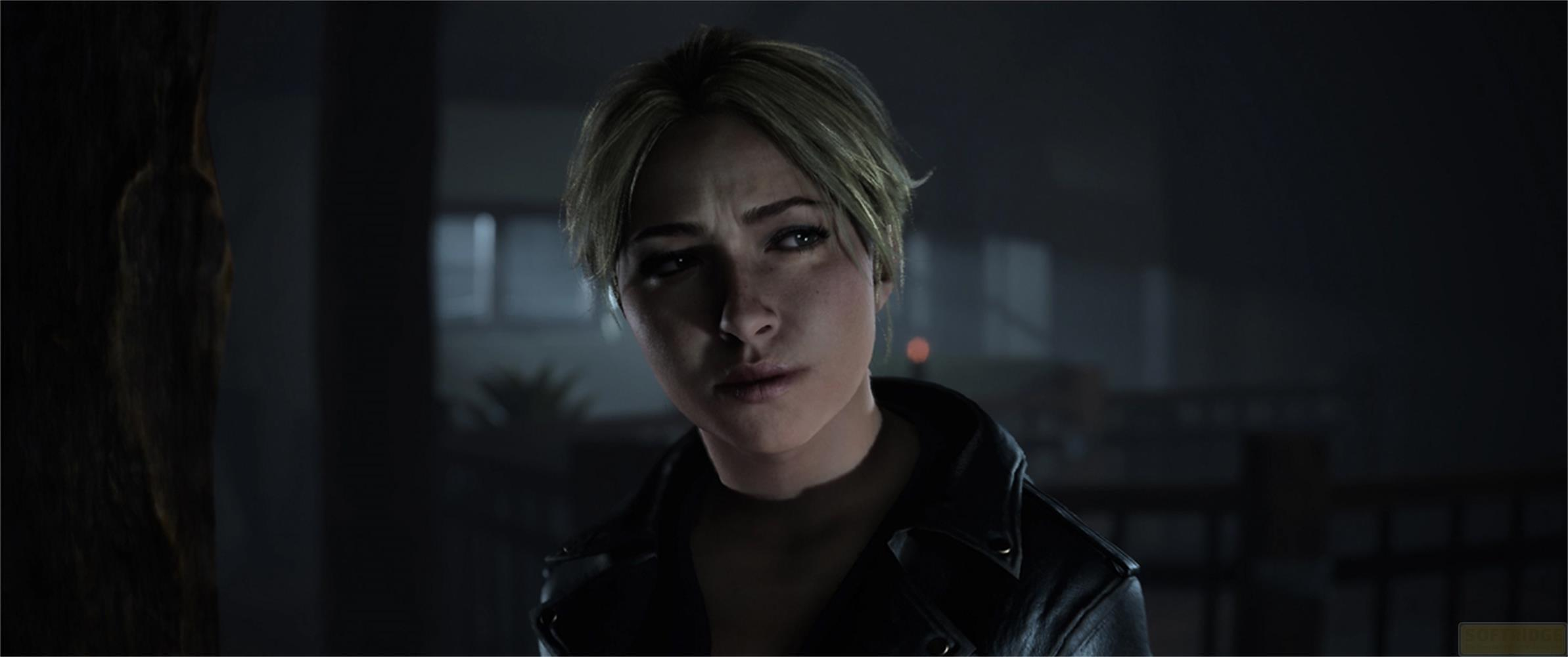 Eine Frau mit blonden Haaren in einer Lederjacke blickt nachdenklich.