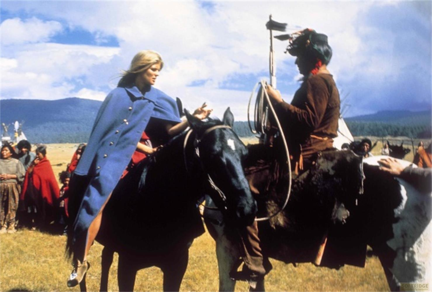 Donna in mantello blu su cavallo nero, uomo nativo americano su cavallo maculato.