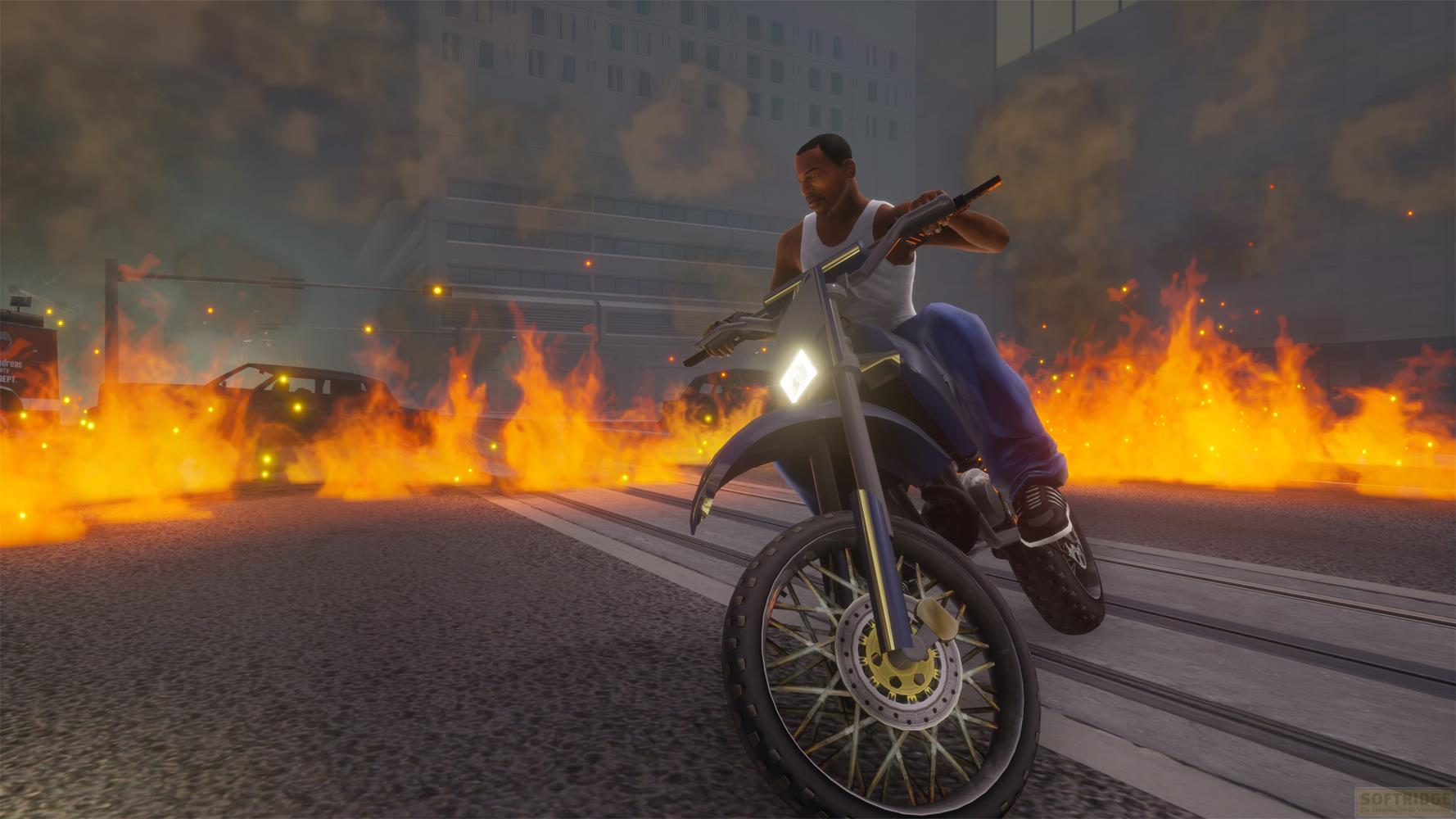 Homme chevauchant une moto dans les flammes devant un immeuble et une voiture en feu.