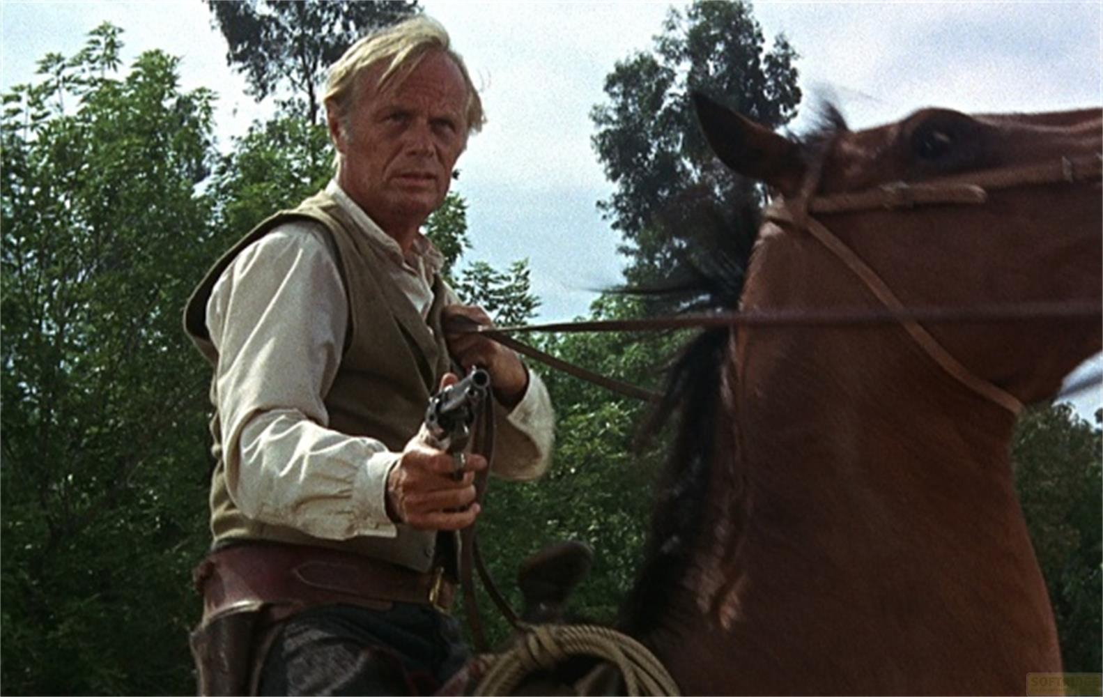 Un uomo in abiti western tiene una pistola su un cavallo.