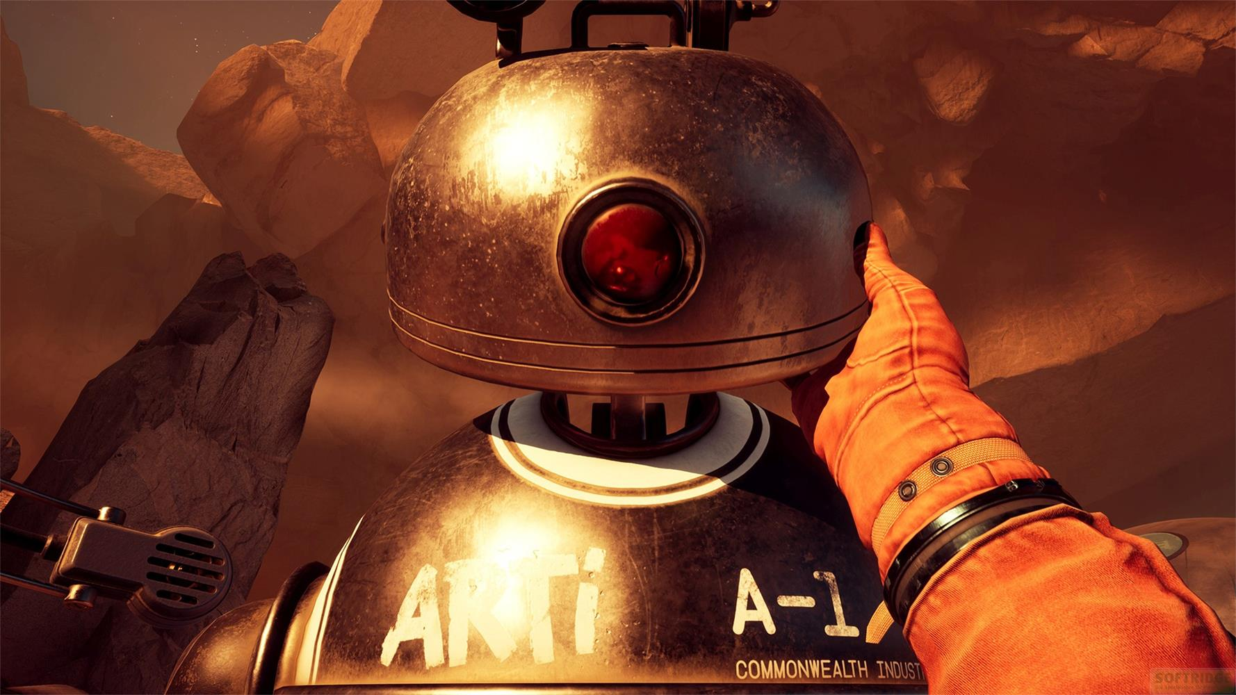 Ein orange gekleideter Arm berührt einen metallischen Roboter mit rotem Auge in einer felsigen Landschaft.
