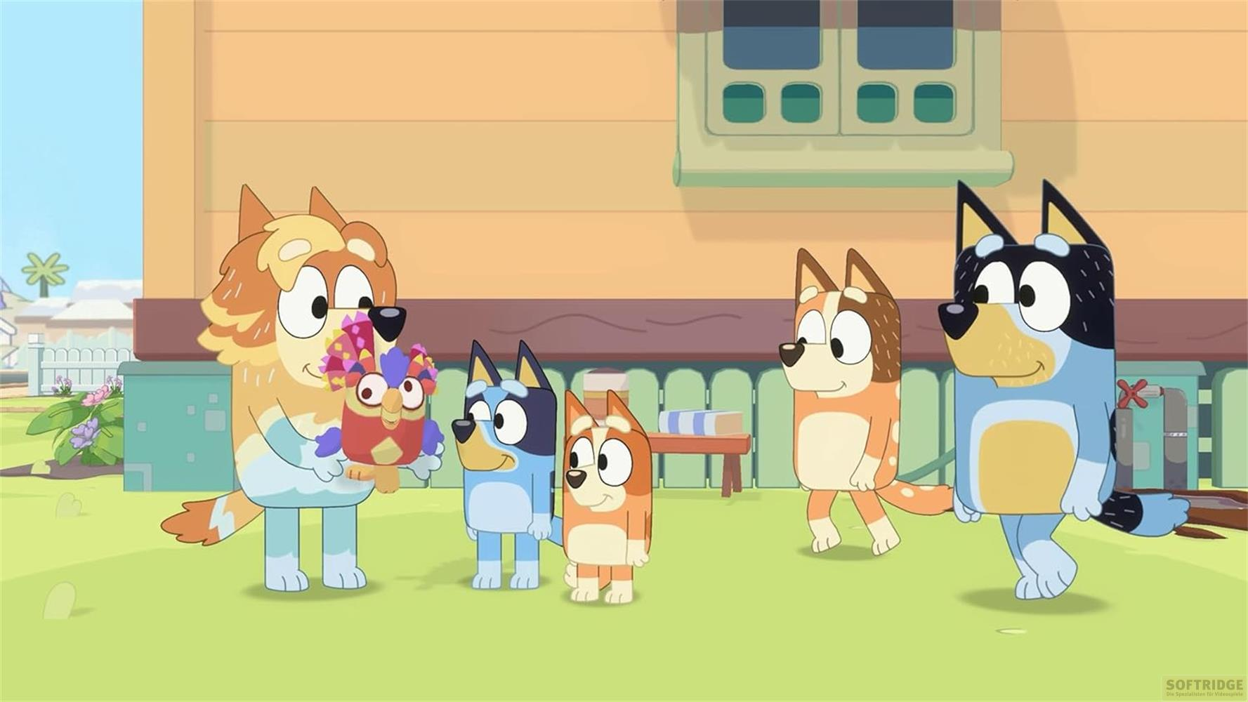 Bandit Hält ein kleines buntes Vogel-Spielzeug, umgeben von seiner Familie.
