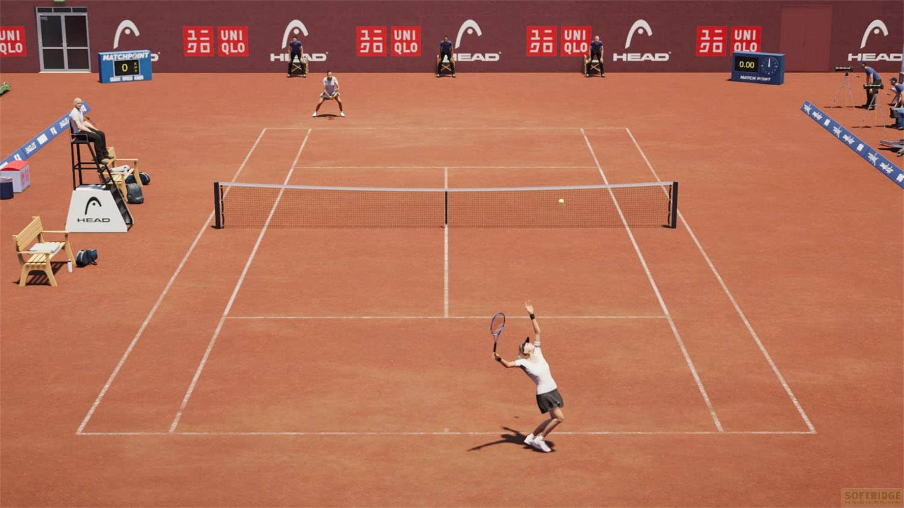 Tennisspielerin beim Aufschlag auf einem Sandplatz mit Werbebannern im Hintergrund.