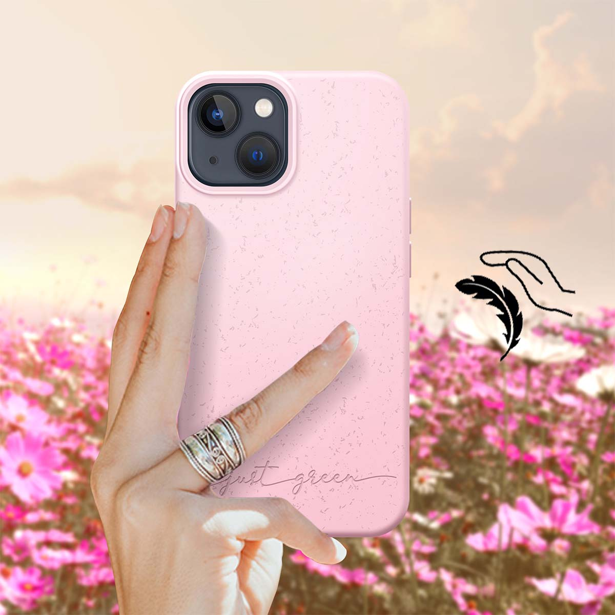 Una mano tiene una cover rosa per telefono davanti a un campo di fiori rosa e bianchi.
