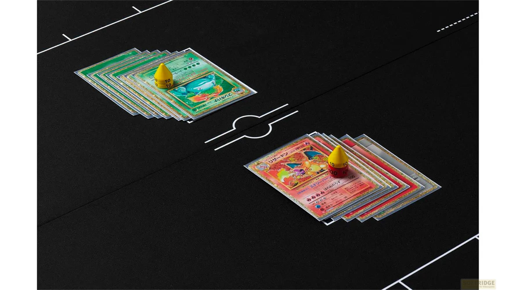 Deux piles de cartes Pokémon sur un tapis noir. Une pile a une carte verte, l'autre un Dracaufeu enflammé.