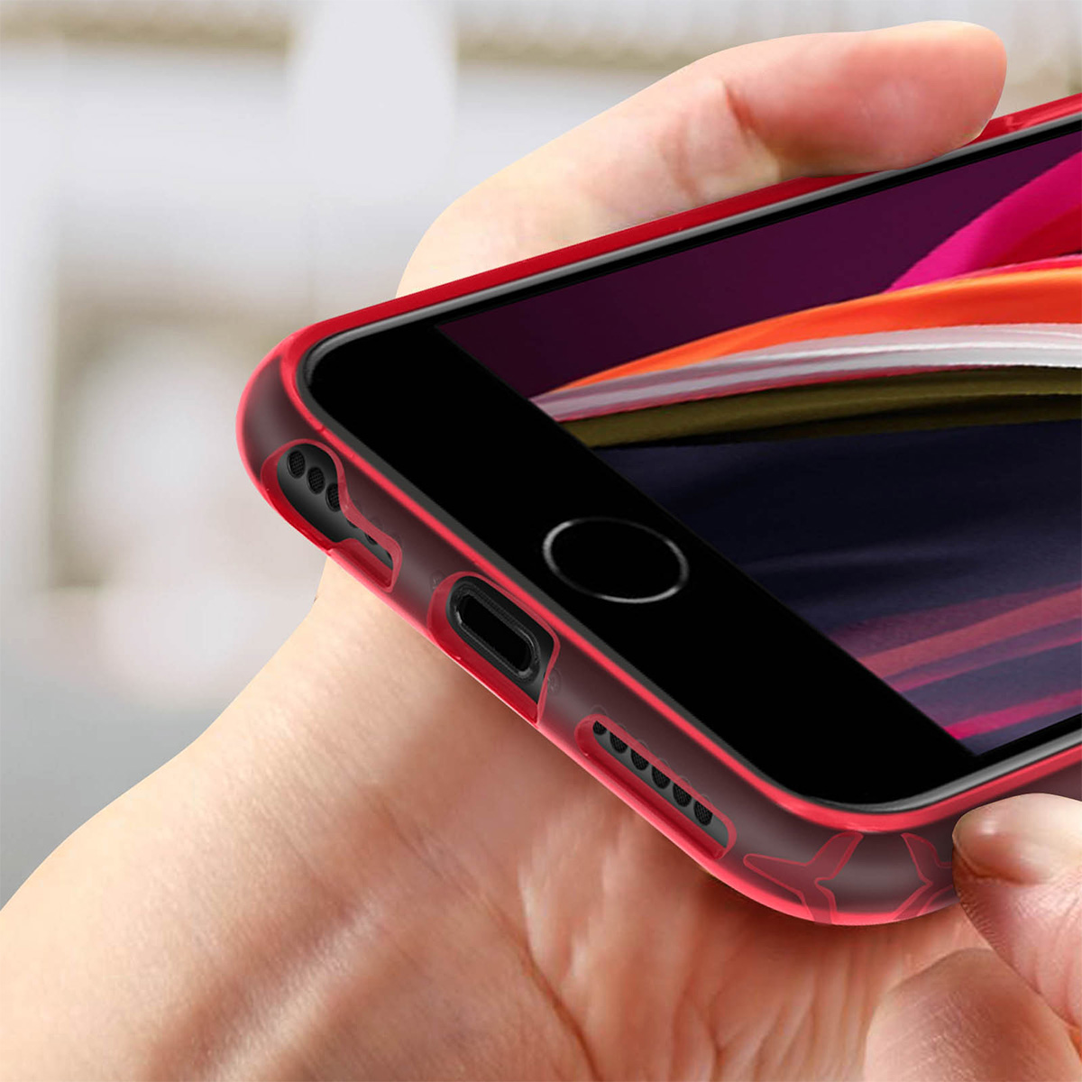 Une main tient un smartphone avec un étui rouge. L'écran affiche des rayures colorées.
