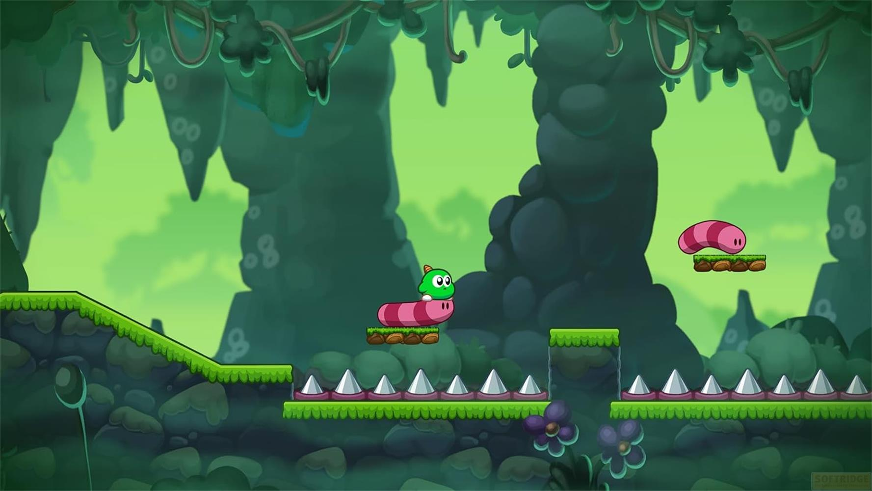 Ein grüner Wurm mit Glubschaugen auf einer Plattform in einer Cartoon-Waldlandschaft.