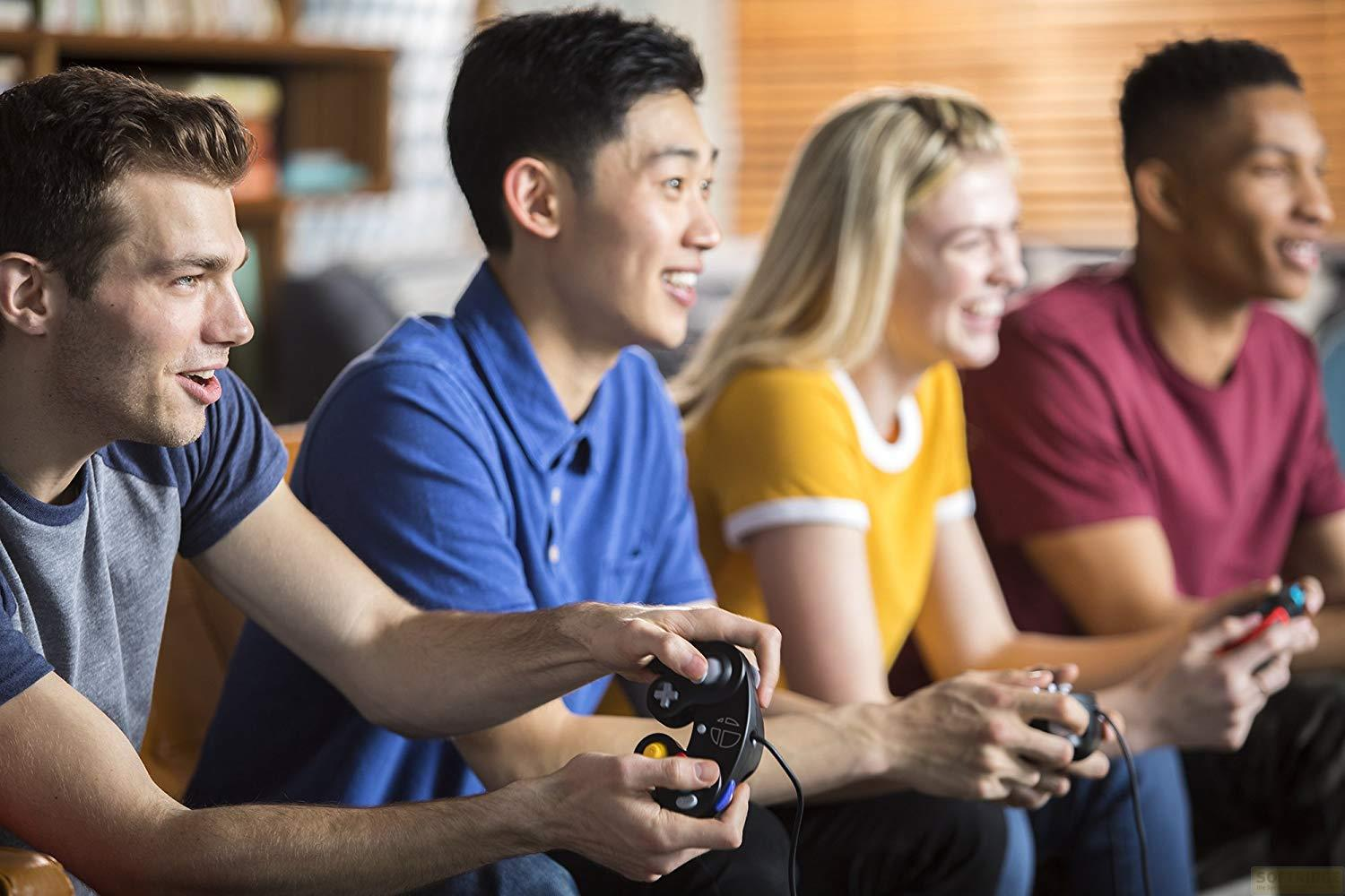 Czterech przyjaciół gra w gry wideo i śmieje się. Siedzą na kanapie.